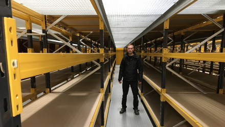 Mand står mellem reoler på et lager