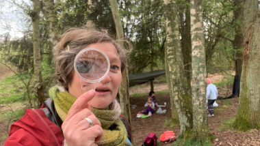 Kvinde holder lup foran øje