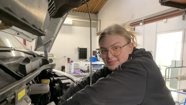 Pige arbejder med en bil på et bilværksted