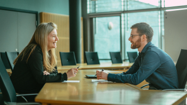 To mennesker sidder over for hinanden ved et bord