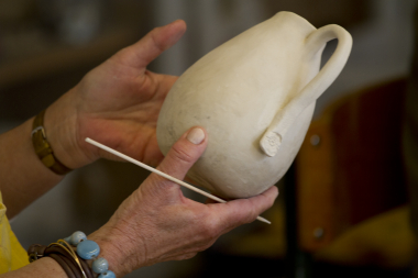 Hænder holder krukke i ler