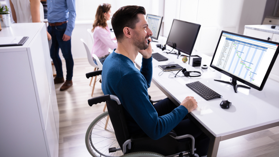 Billedet viser en mand der arbejder fra sin kørestol