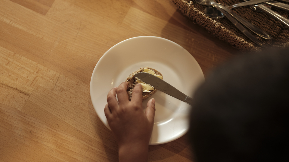 Børnehænder smører et brød