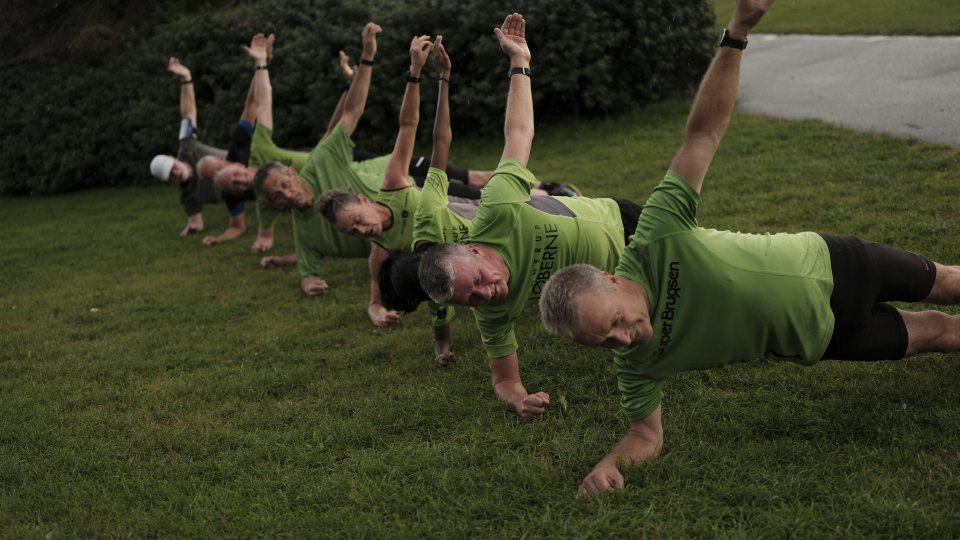 Gruppe af mennesker styrketræner udenfor