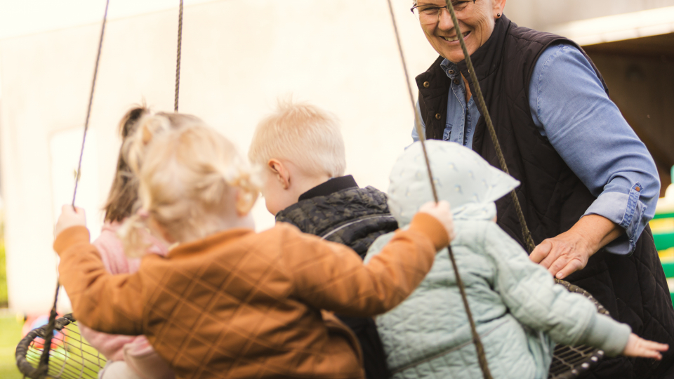 Børn på gynge med voksen ved siden af