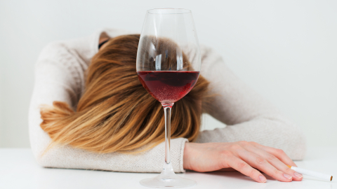 Kvinde med glas med rødvin og cigaret